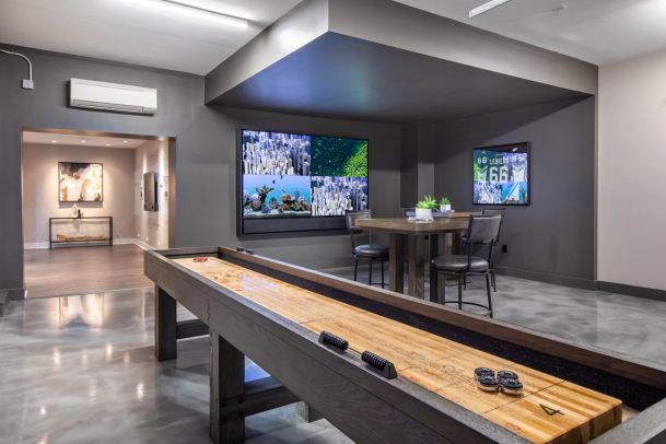 A modern bar area with glass-front cabinets, backlit with soft lighting, and a marble countertop that illuminates in warm yellow tones.